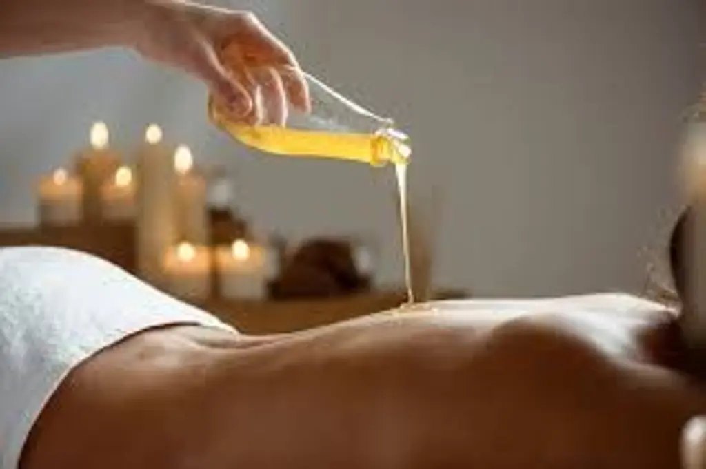 Rituel ayurvédique : huile chaude versée sur le dos à la lueur des bougies